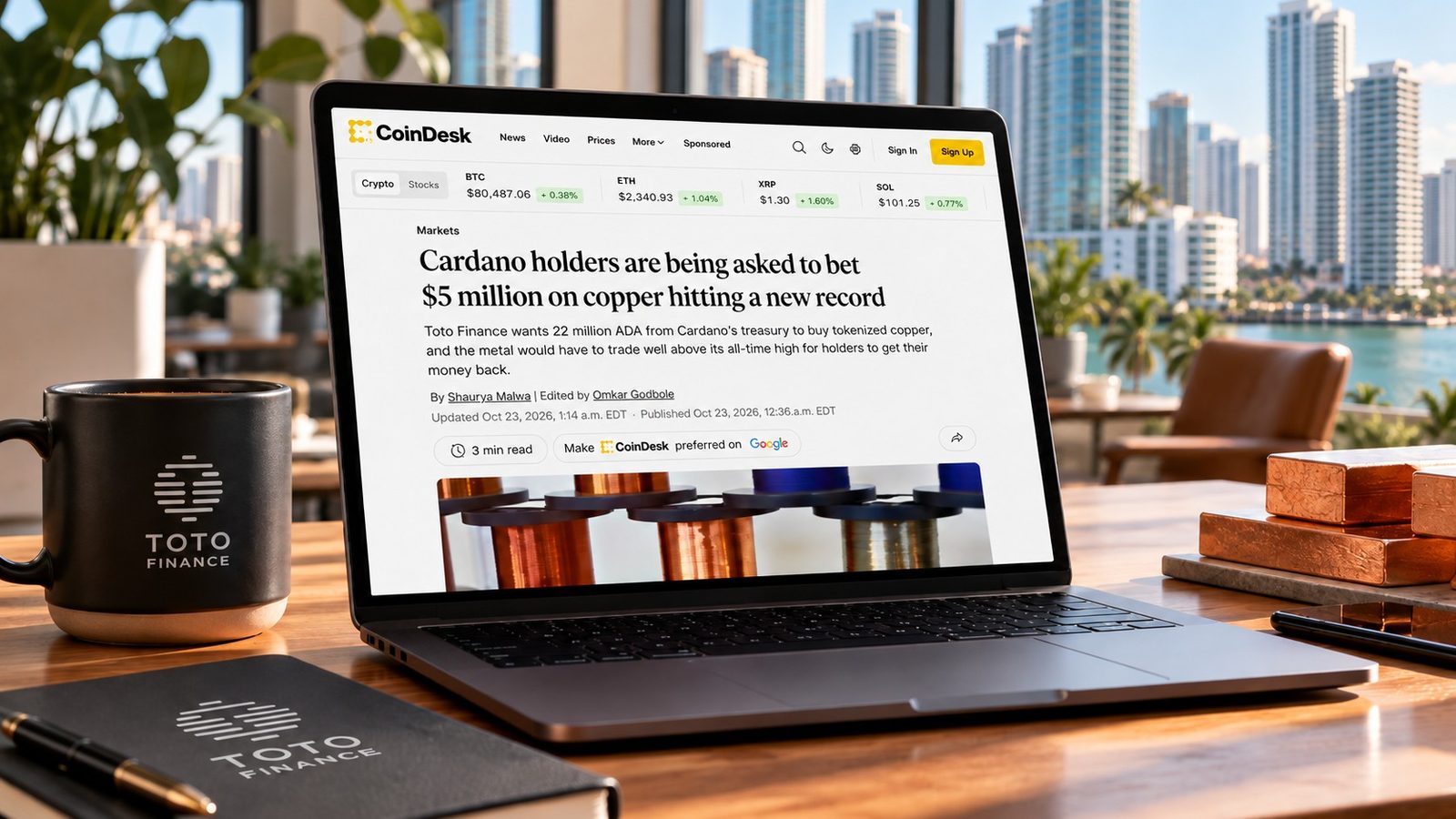 Laptop in the Toto Finance Miami office showing the CoinDesk article Cardano holders are being asked to bet 5 million dollars on copper hitting a new record, beside a Toto Finance mug and copper cathode samples
