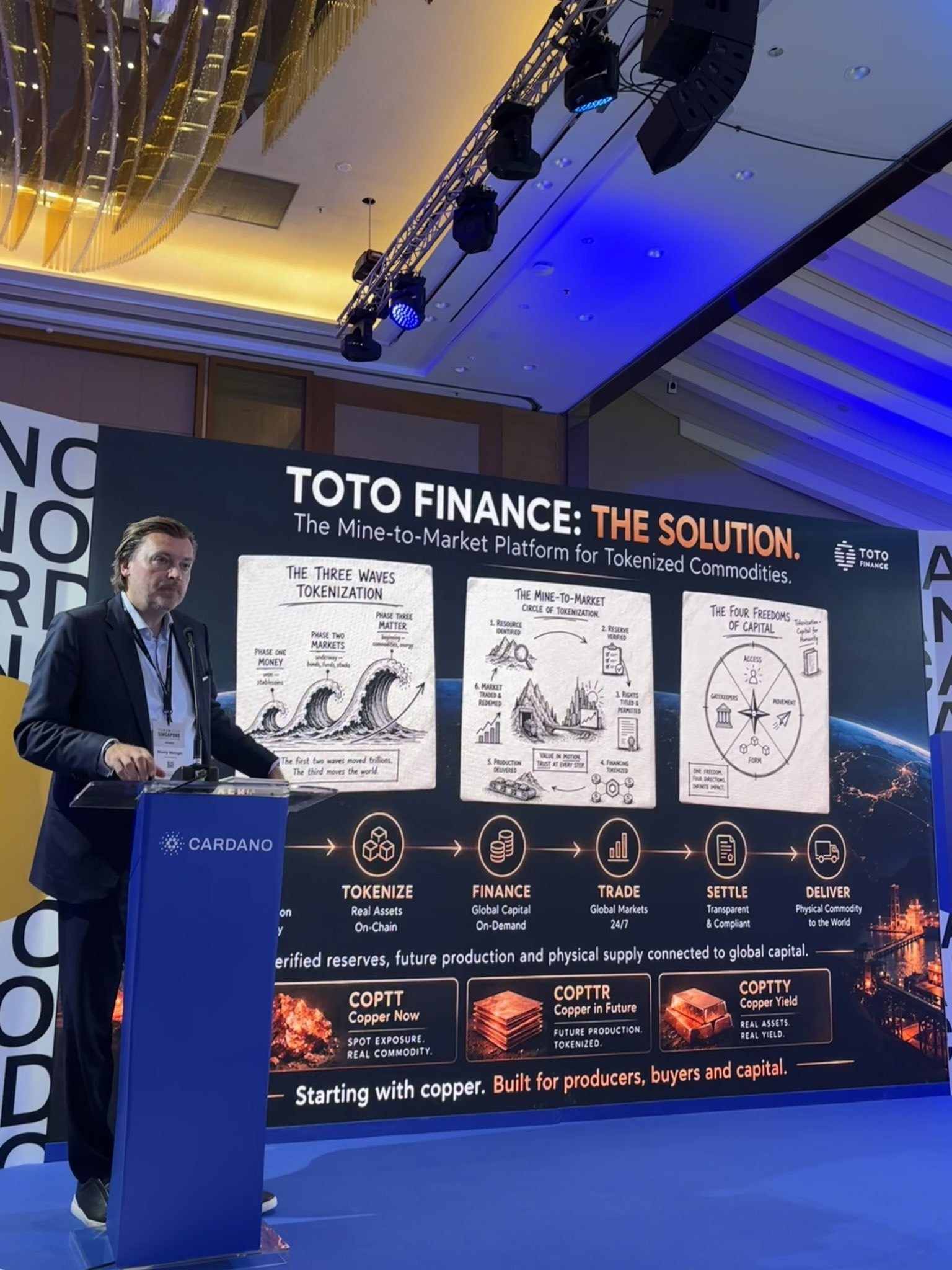 Monty Metzger speaking at the Cardano stage at TOKEN2049 Singapore in front of the slide Toto Finance: The Solution, the mine-to-market platform for tokenized commodities
